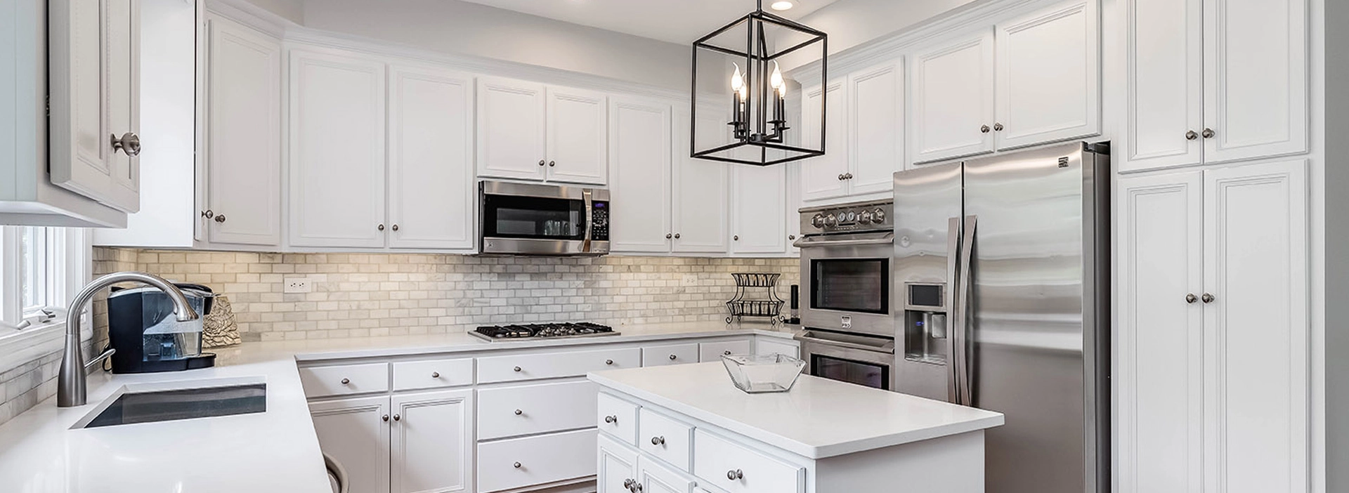A kitchen with white cabinets and black accents.